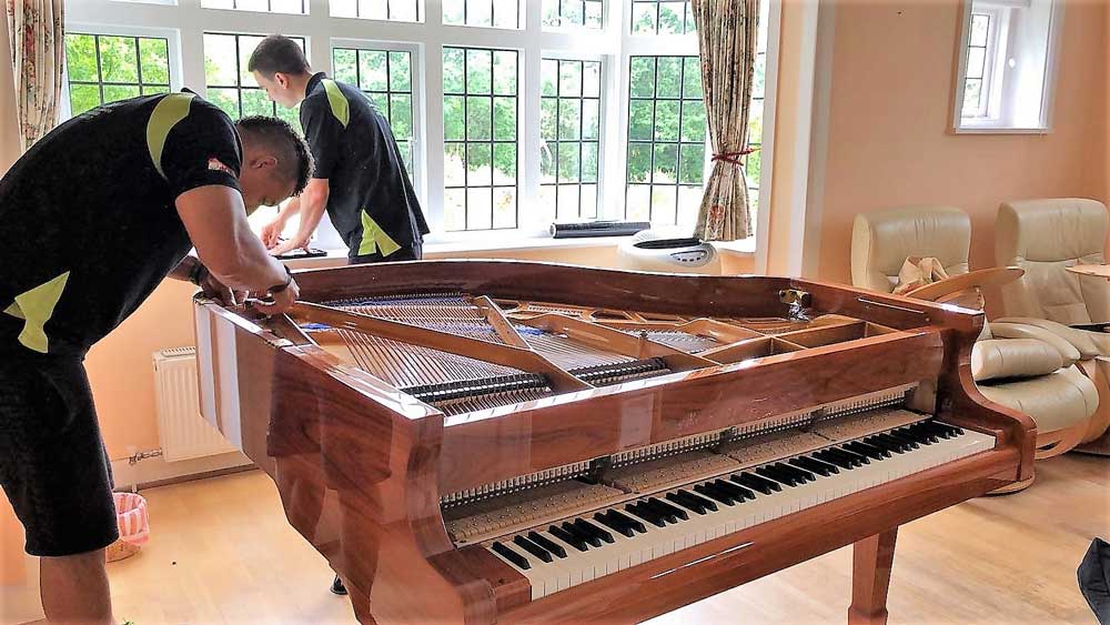 Piano movers in London preparing protective wrapping and moving equipment